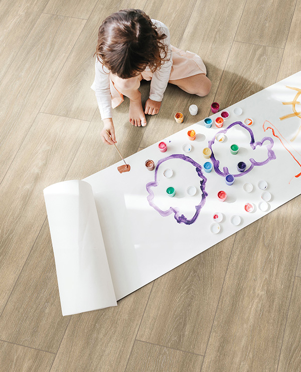 Child plays with paints on beige ShoreFlor™ Waterproof Laminate flooring from Tarkett Home